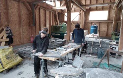 Deux stagiaires en plein exercice pratique de taille de lauzes calcaires