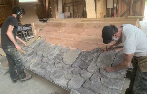 Deux stagiaires en plein exercice pratique sur une maquette de lauzes en schiste