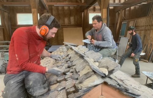 Trois stagiaires en plein exercice pratique sur une maquette de lauzes en schiste
